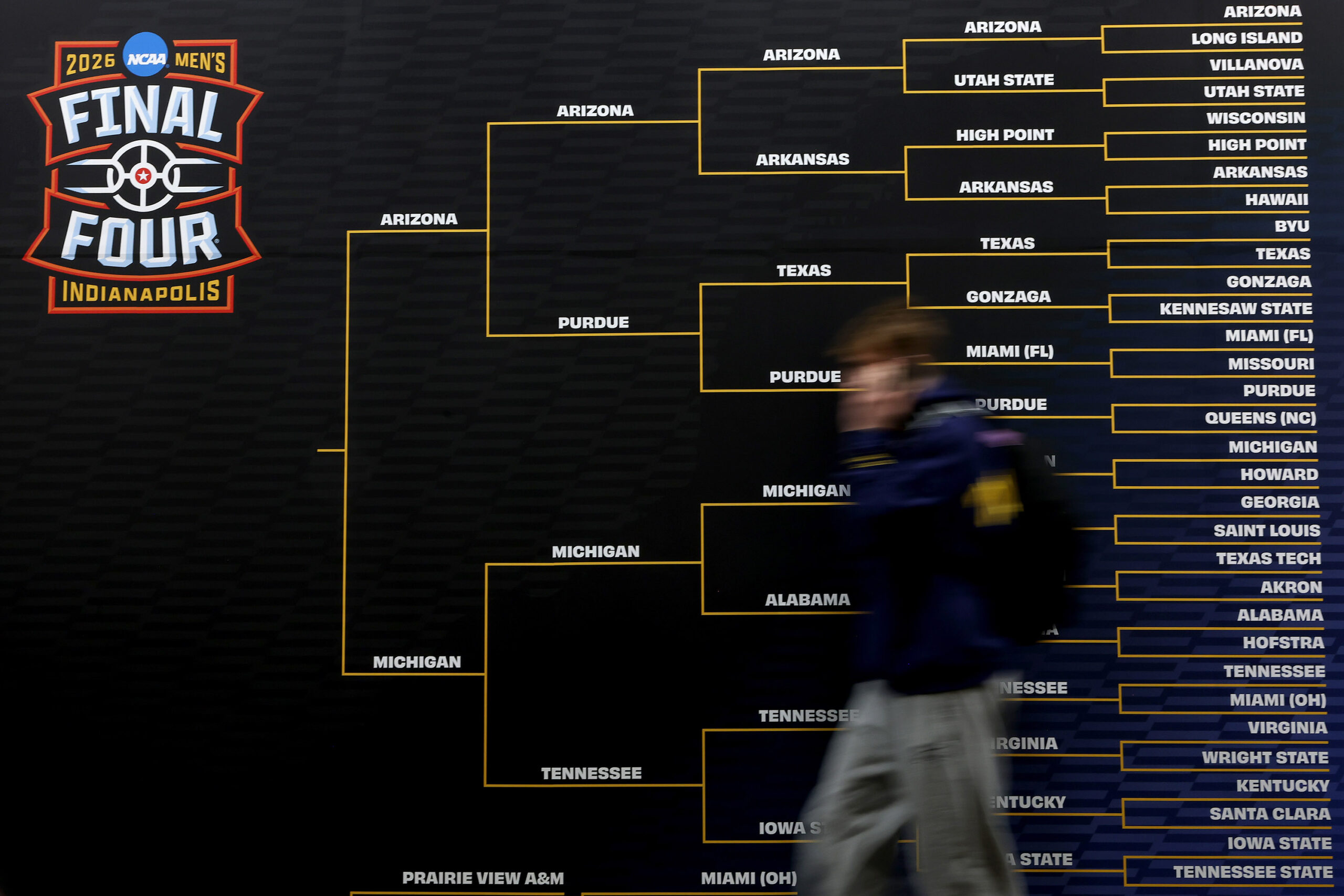person walks past a large bracket during the Practice Day of the 2026 NCAA Men's Basketball Tournament at Lucas Oil Stadium on April 03, 2026 in Indianapolis, Indiana.