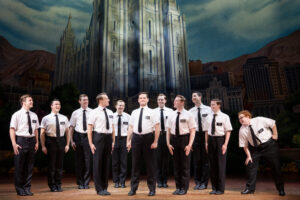 In "The Book of Mormon" a group of Mormon missionaries dressed in white shirts and black ties stand together.