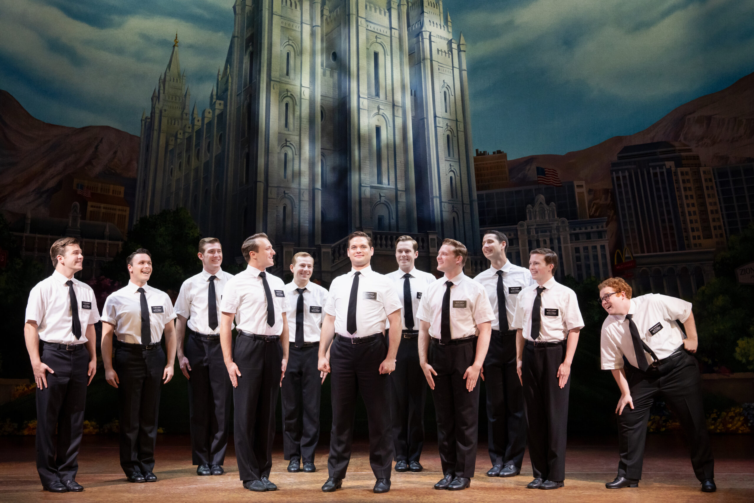 In "The Book of Mormon" a group of Mormon missionaries dressed in white shirts and black ties stand together.