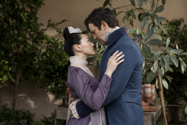 In "Bridgerton" Season 4 Part 2, a woman dressed in purple maid attire stands and embraces a man dressed in high-class attire.