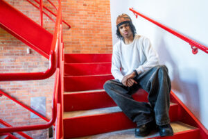 Man sitting on a red staircase wearing white.