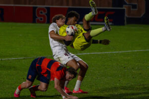 Louisville goalie Nathaniel Abraham falls to the ground after leaping over Syracuse midfielder Bryson Rodriguez for the ball on Saturday, October 10, 2026, at the SU Soccer Stadium.