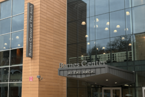 A large glass building with a grey sign on it reads "Barnes Center At the Arch."