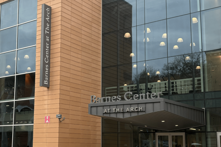 A large glass building with a grey sign on it reads "Barnes Center At the Arch."