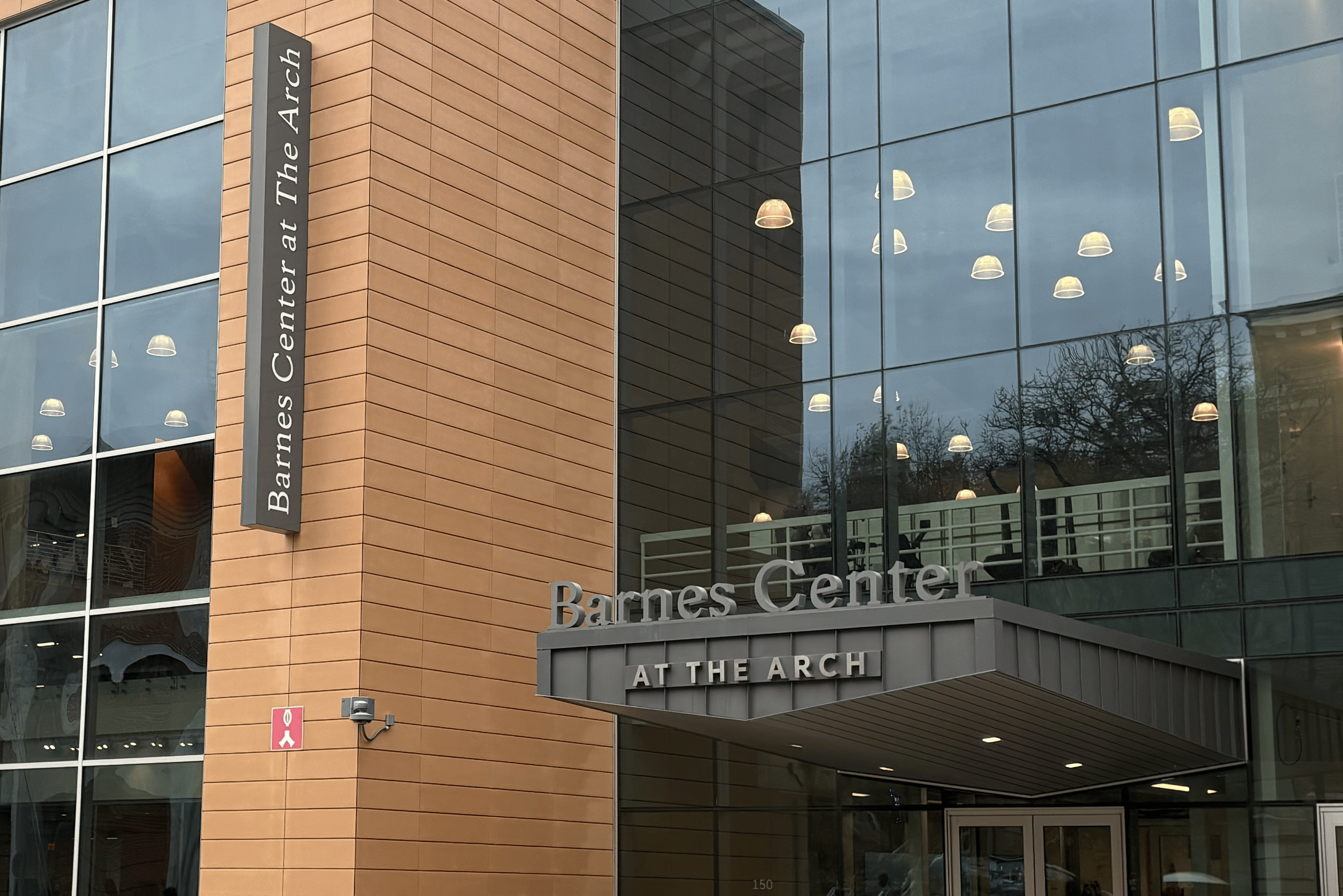 A large glass building with a grey sign on it reads "Barnes Center At the Arch."