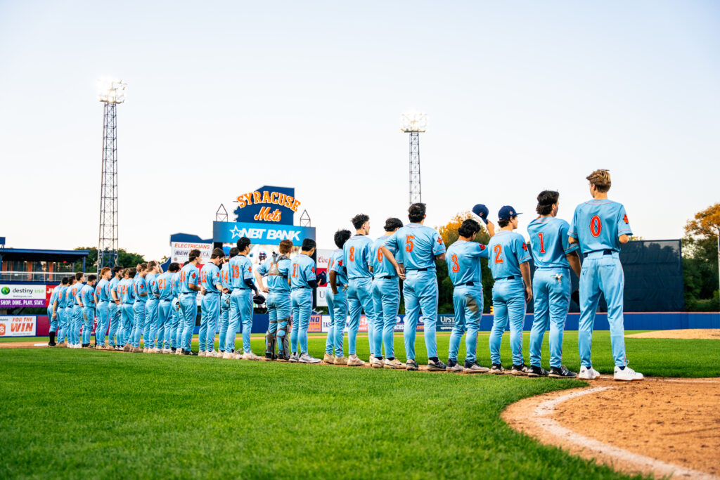 Syracuse Club Baseball players stand on the third baseline for the National Anthem.
