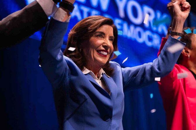 NY State Governor Kathy Hochul celebrates on stage alongside State Comptroller Tom DiNapoli (left) and Hochul's running mate Adrienne Adams (right).