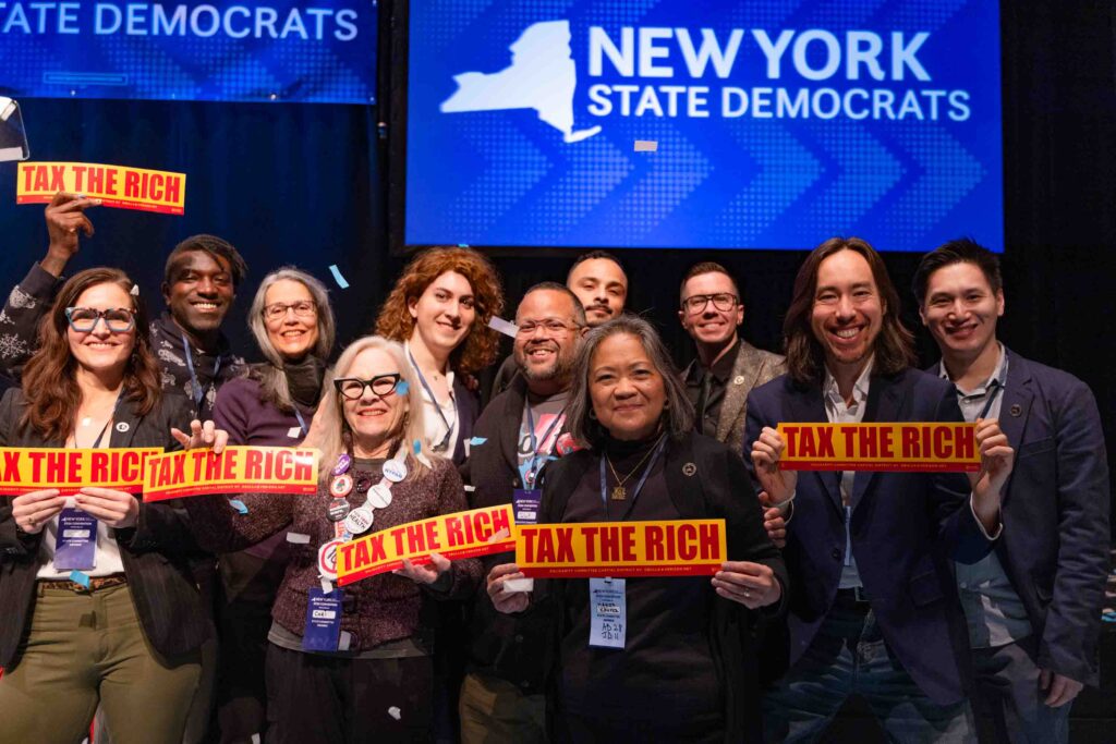 Attendees of the Democratic Convention for the state of New York pose with signs that say 