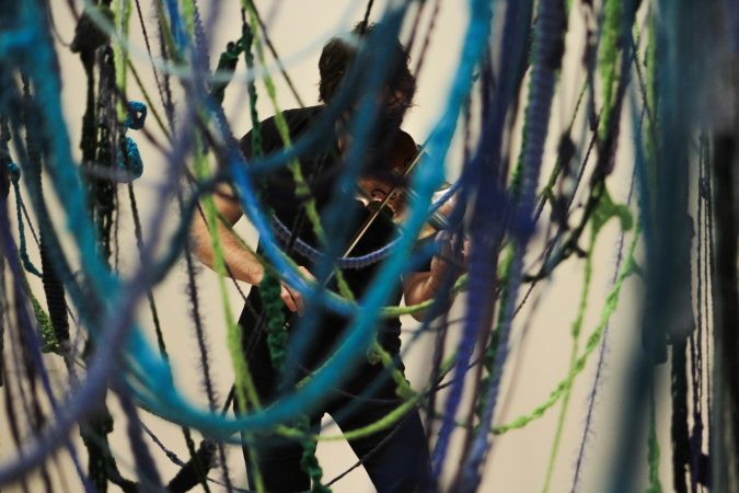 Fulmer plays the violin standing in a gallery at the Everson.