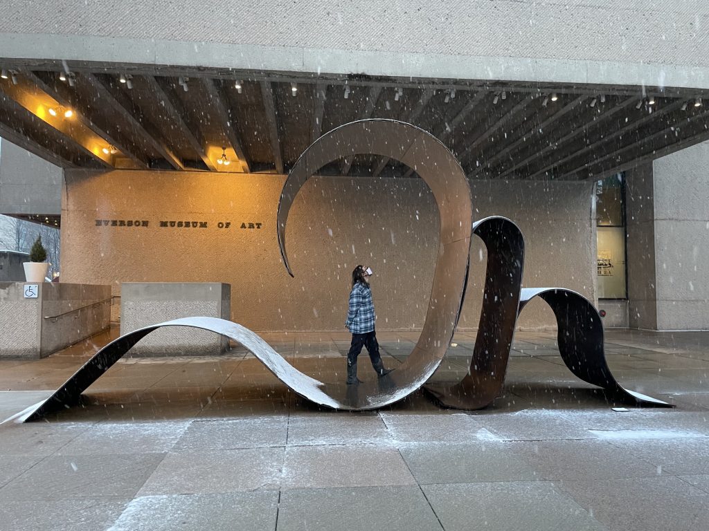 Fulmer stands inside a large metal sculpture outside the Everson as snow falls around him.
