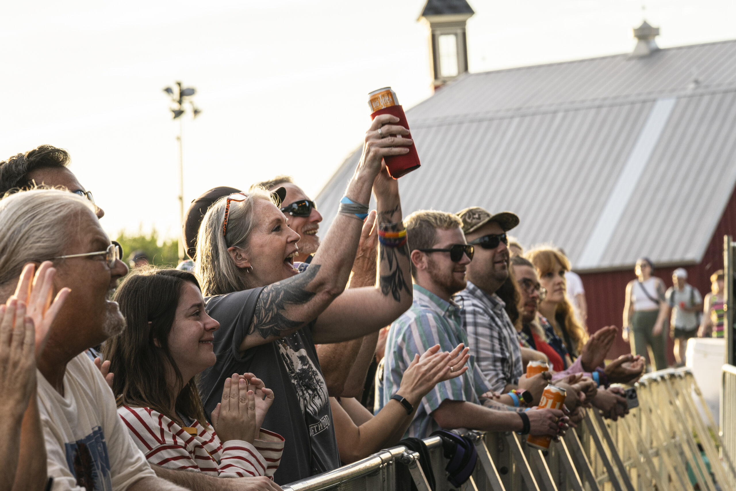 A fan raises a drink and cheers during I’m With Her’s set at Beak & Skiff Apple Orchards in Lafayette, N.Y., on Friday, July 25, 2025.
