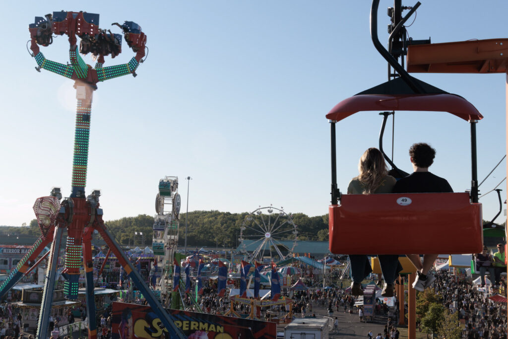 Fair goers sit on a ride overlooking the fair grounds