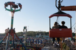 Fair goers sit on a ride overlooking the fair grounds