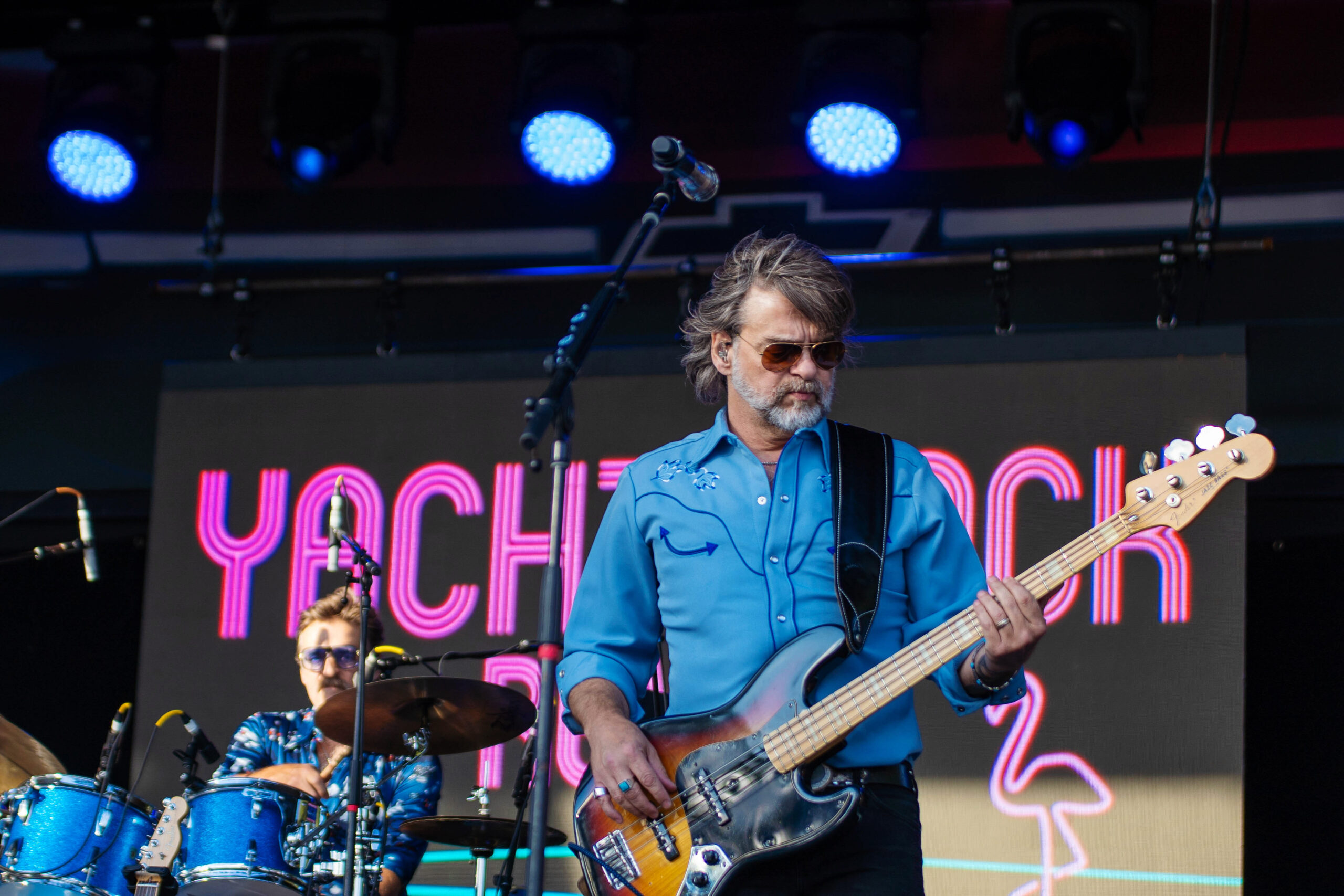Yacht Rock Revue guitarist mark Dannells in blue shirt plays electric guitar.