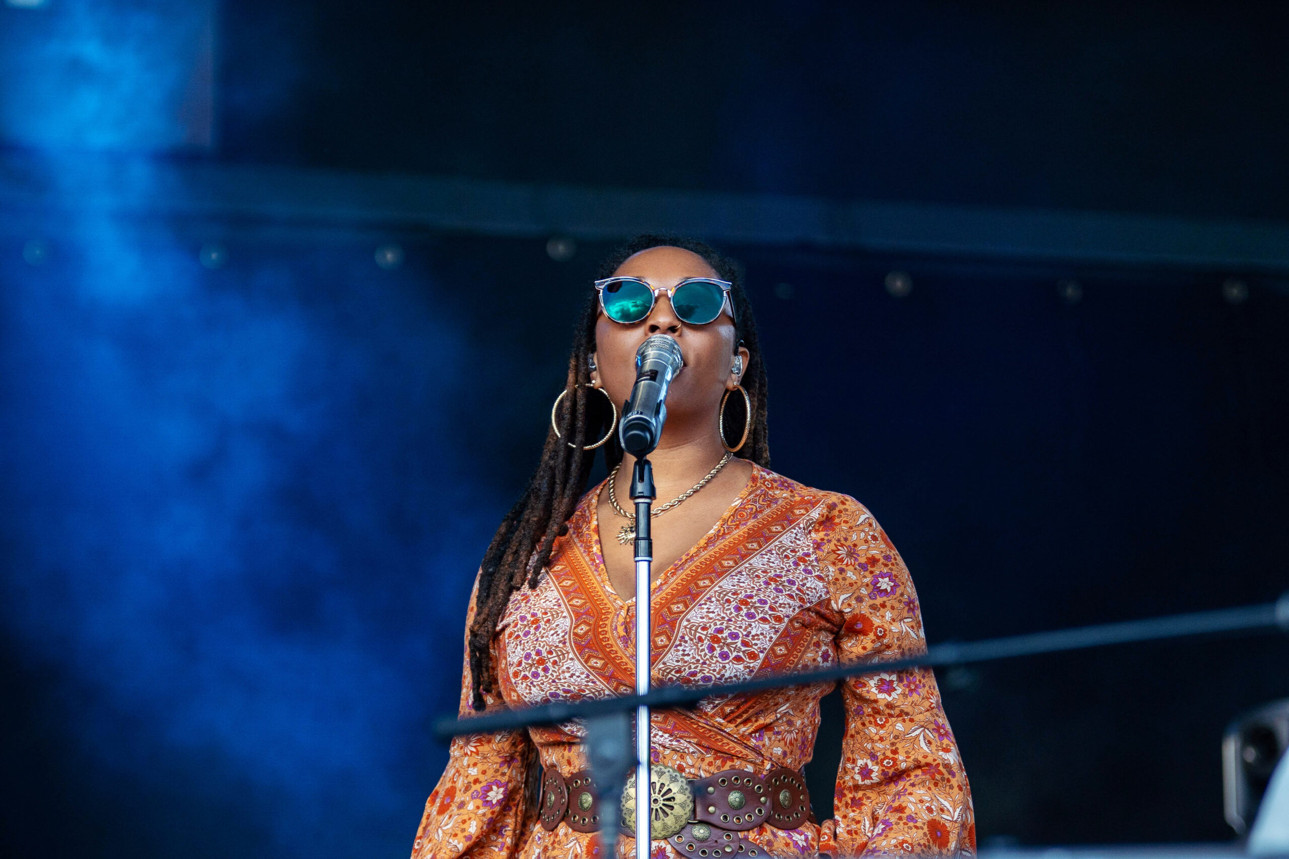Yacht Rock Revue vocalist Kourtney Jackson in orange dress sings into micophone.
