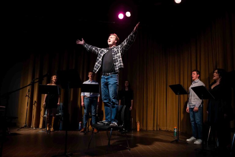 Reed Grayner, a sophomore musical theatre major, performs as Jon from the musical Tick, Tick... BOOM! during Black Box Player's performance at Syracuse Stage on Nov. 20, 2025. Behind him, other cast members sing chorus as they perform "Sunday," the fourth song in the musical.