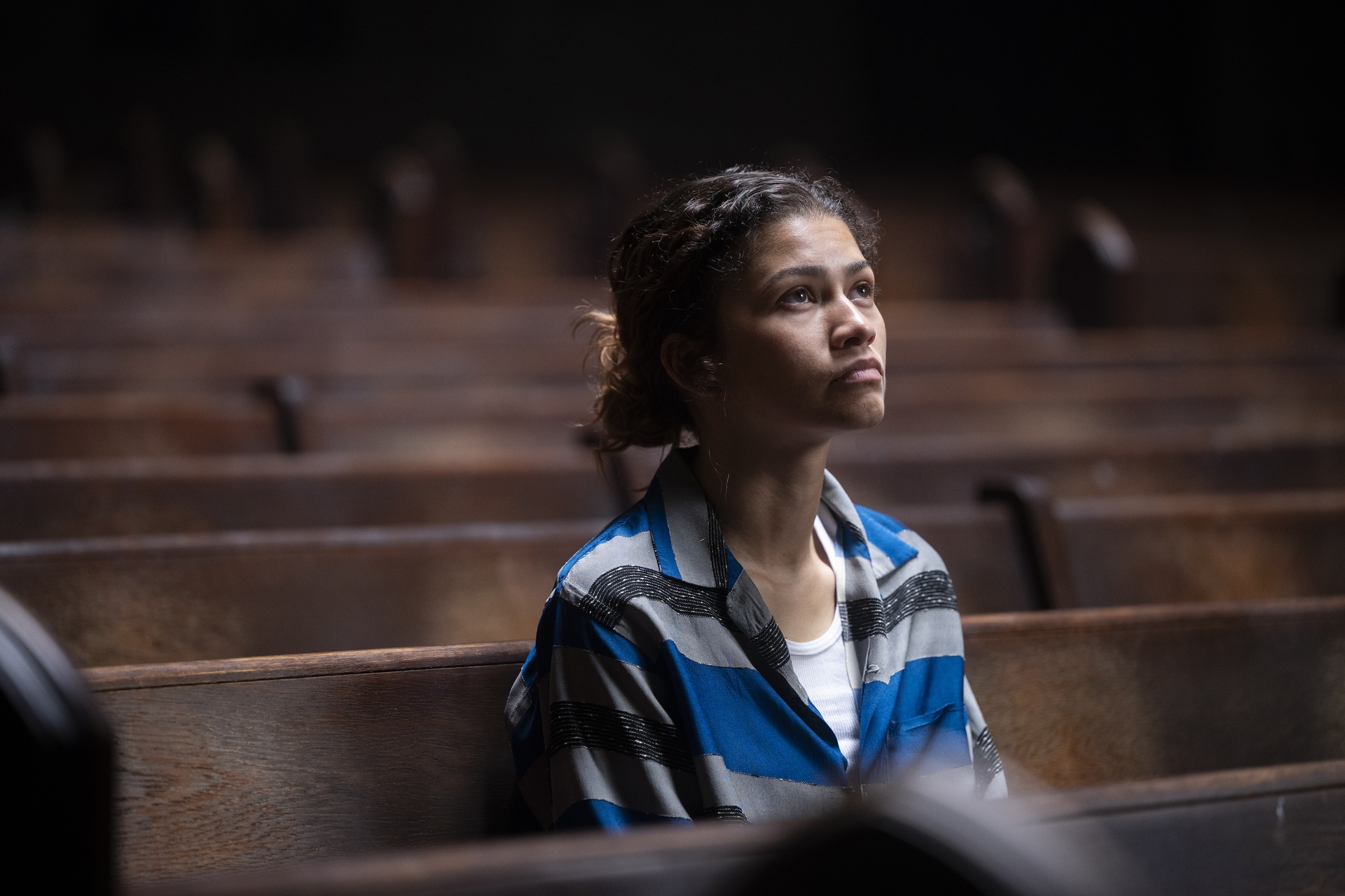 In "Euphoria" Season 3 Rue sits alone in a wooden pew in a church, staring up.