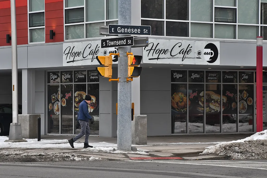 A man walking by Hope Cafe in Syracuse, on the corner of Townsend and Genessee