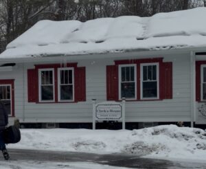 A building with red and white exterior and a snowy front have a bakery and cafe sign out front.