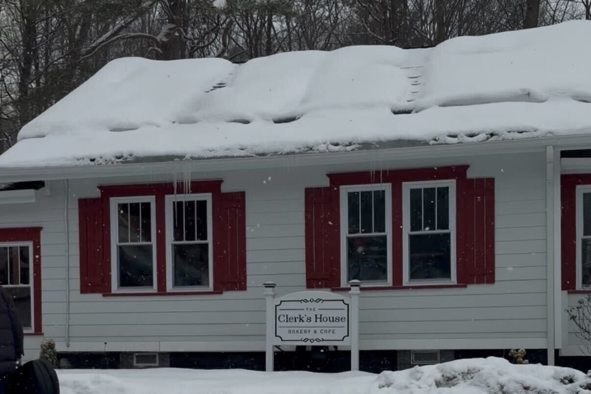 A building with red and white exterior and a snowy front have a bakery and cafe sign out front.