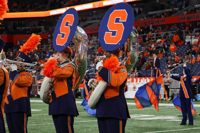 Michael Gaither, right, playing his trombone for the Syracuse University Marching Band in the JMA Wireless Dome.
