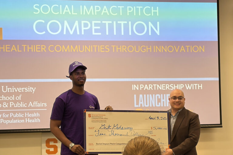 First place winner Souleymane Bah and Vicente Cuevas, undergraduate student engagement manager for the Lerner Center, holding the check for the $5,000 grant prize.