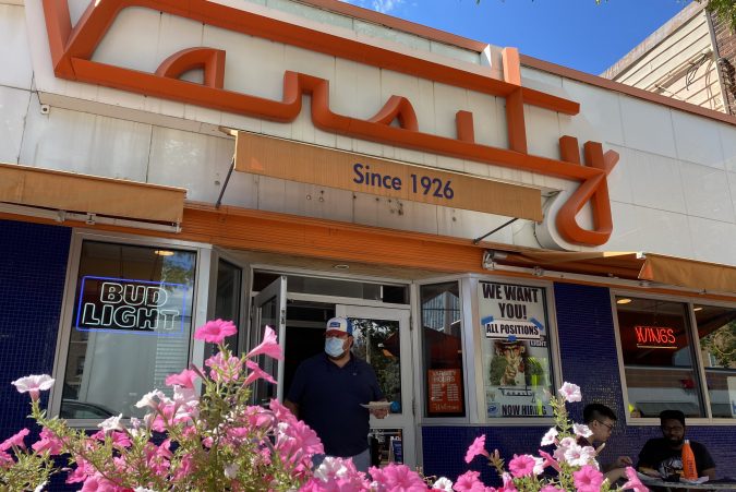A masked man walks out of varsity pizza