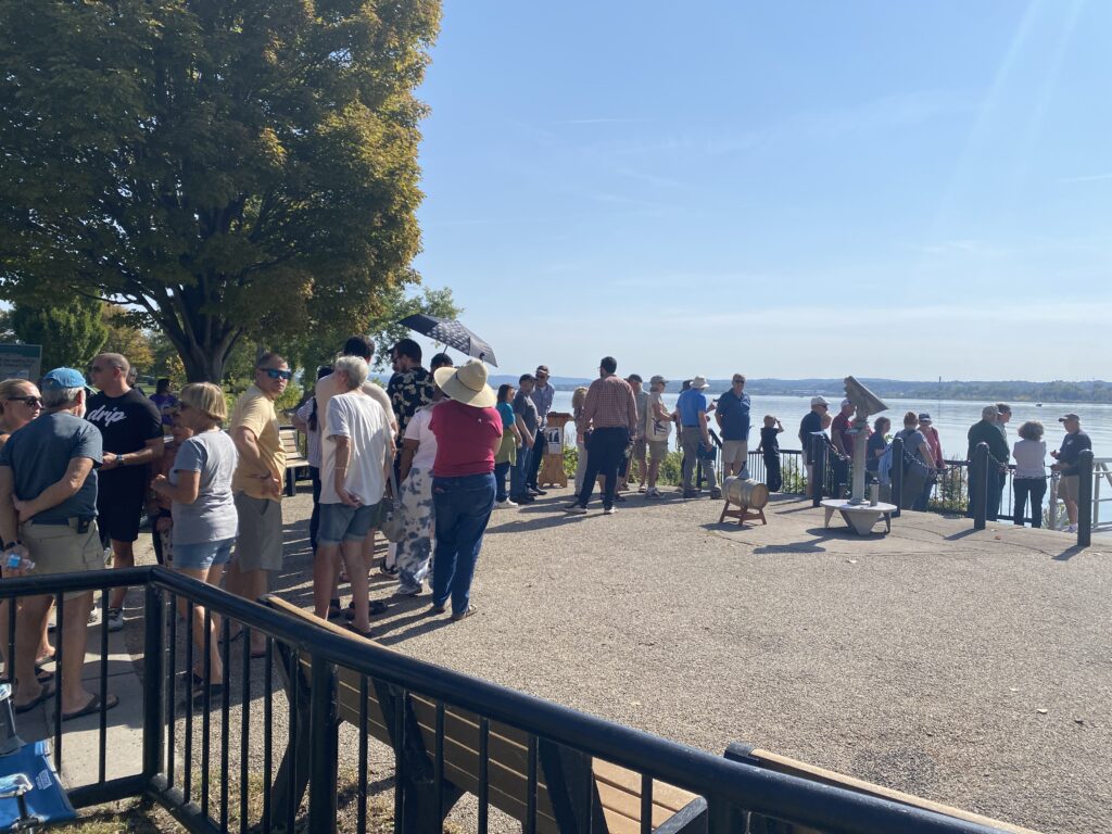 A line extends from the dock at Onondaga Lake toward the Salt Museum as people wait to board the Seneca Chief.