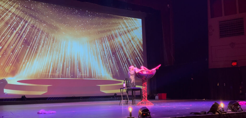 Performer Gina the Machina dances in a large martini glass
