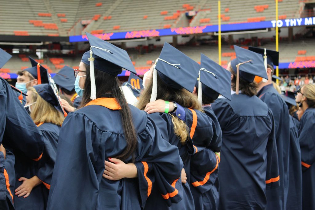 2020 SU graduates share a moment during the September 19, 2021 Commencement ceremony in the Dome.