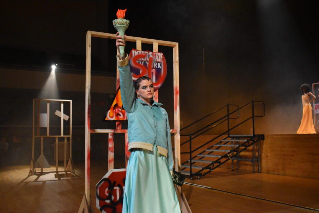 Woman in statue of liberty dress holding up torch