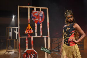 fashion show model in a tight shirt and skirt in front of a grafittied panel