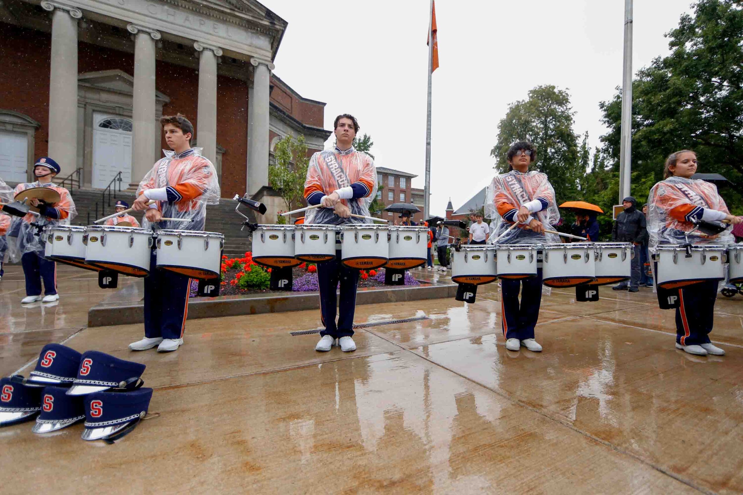 The Syracuse marching band's drumline plays in the rain Saturday in front of Hendricks Chapel.
