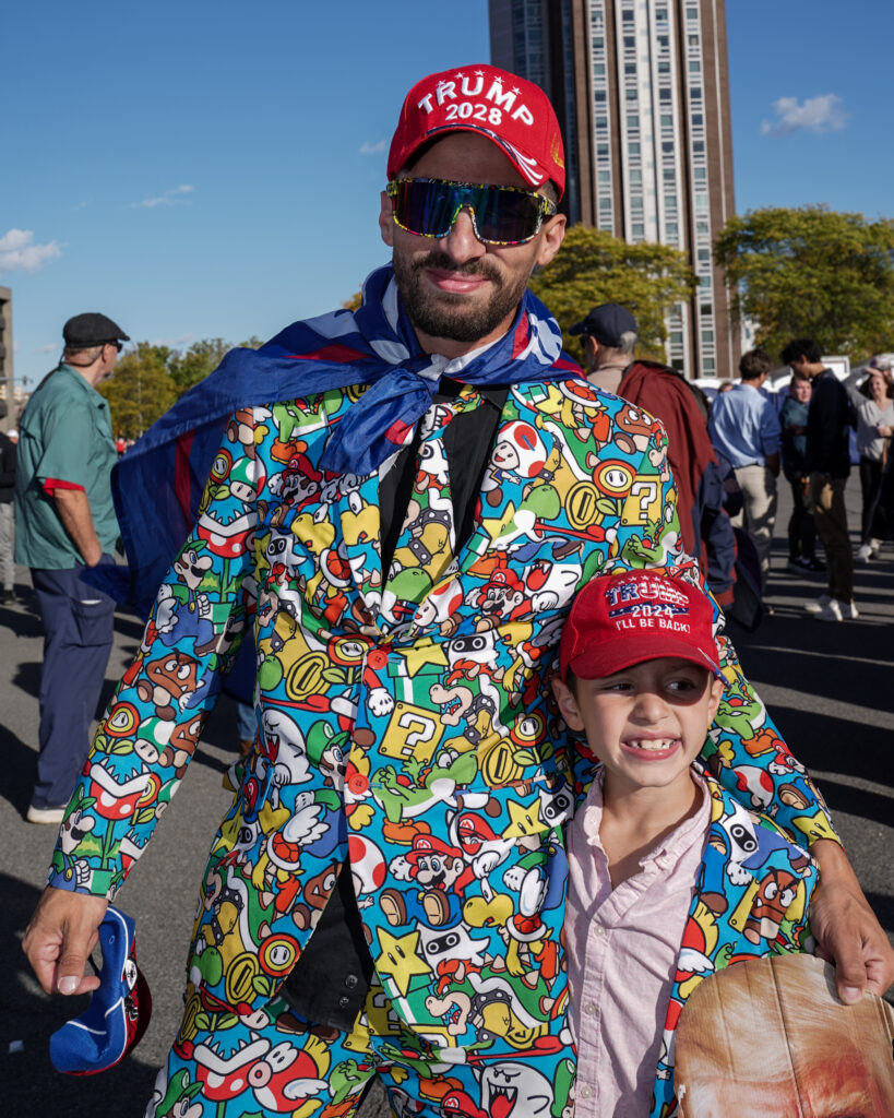 Tyler Clapps and his son, Elijah, 7, of Camden, NY, dress in matching Mario suits at the Trump rally outside of the OnCenter on Friday, Oct. 9, 2026.