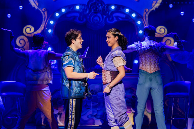 In "& Juliet" Francois and May stand together, smiling at on another.