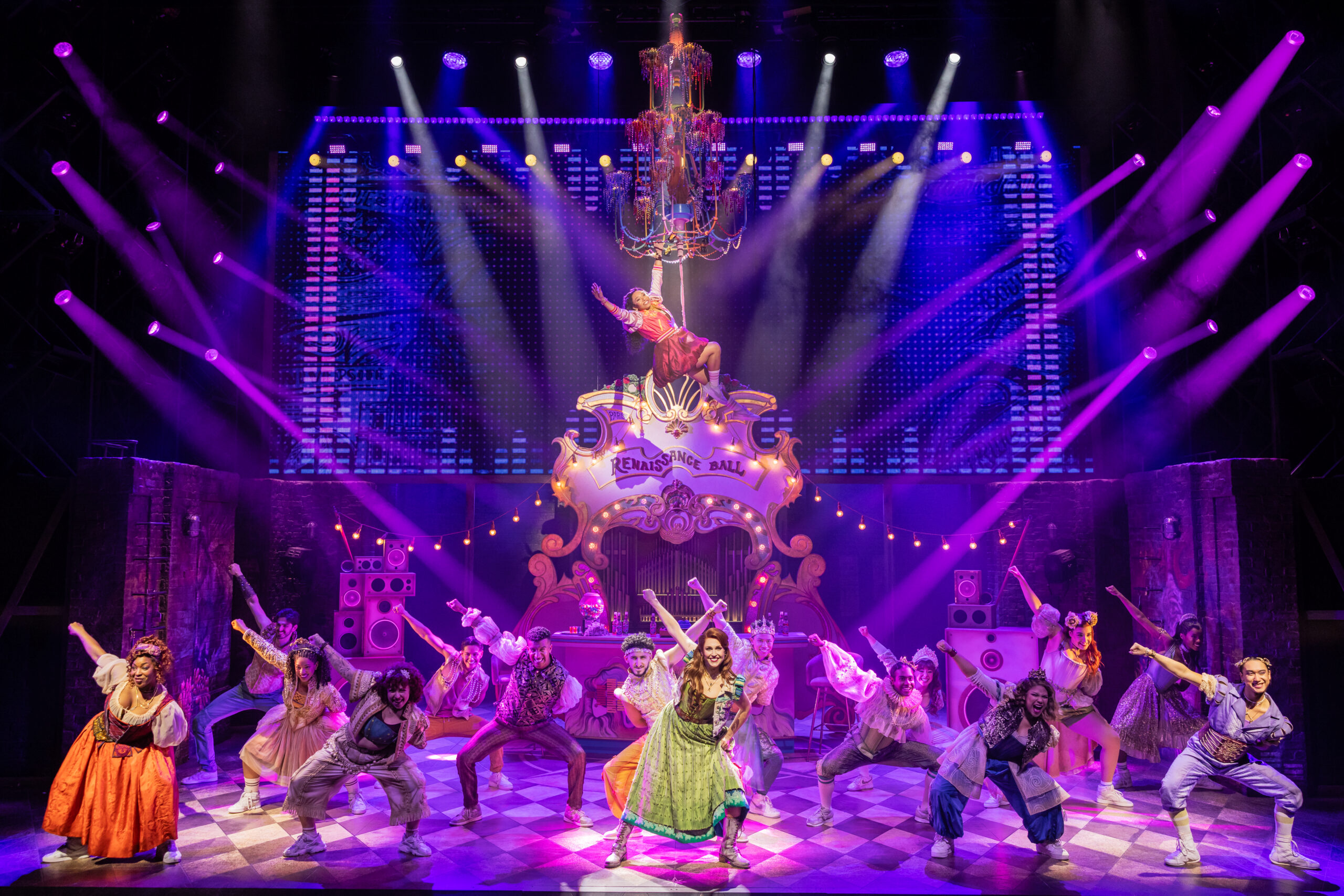 In "& Juliet" the cast dances on stage under purple lights as Juliet hangs from a chandelier above them.