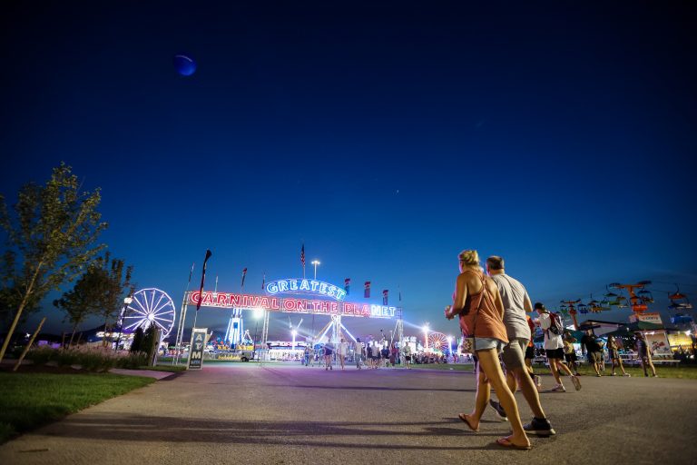 A pair of fairgoers walk toward Midway at the New York State Fair.
