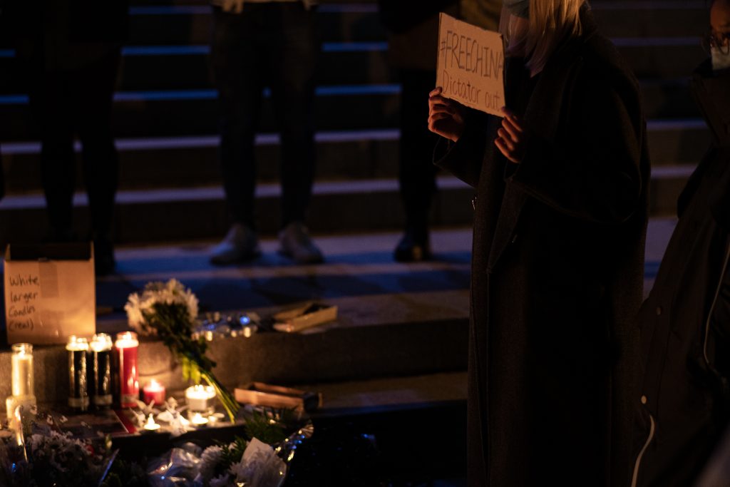A protester holding a poster with slogan writing “#FreeChina, Dictator Out in front of Hendricks Chapel on November 28th, 2022.