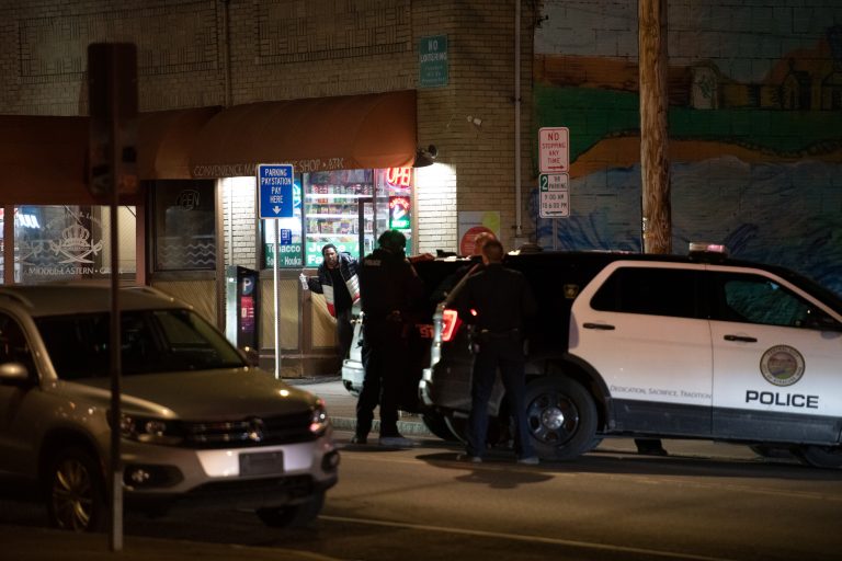 Police speak with the suspect as he briefly steps outside the door. Syracuse Police responded to a hostage situation involving one suspect a at least 2 hostages at Hitham's Pop Shop, a convenience store on Westcott St in Syracuse, around 9pm on Easter Sunday. Photo by Ryan Brady. Taken 4/17/22.