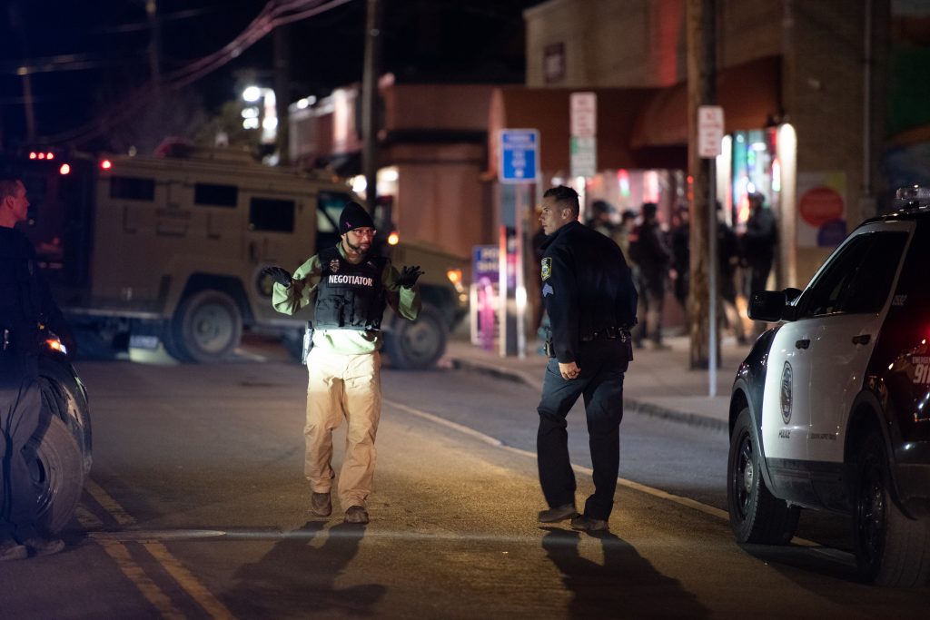 The hostage negotiator walks back towards tehe police line from the front door of the store. On Easter Sunday at 8:44 PM, Syracuse Police responded to a hostage situation involving one suspect a at least 2 hostages at Hitham's Pop Shop, a convenience store on Westcott St in Syracuse. Photo by Ryan Brady. Taken 4/17/22