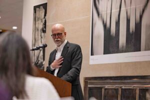 Bruce Strong, associate professor in Visual Communications at Newhouse and the Alexia Endowed Chair, speaks during the opening night of his Call to Me, Balkans photo exhibition in Panasci Lounge located on the third floor of Schine Student Center. The exhibition features photos, all of which were made on his iPhone, from his 2023 sabbatical and two successive trips to Bosnia. Claudia Strong, an adjunct in Visual Communications at Newhouse and also Bruce’s wife, curated and designed the exhibition.