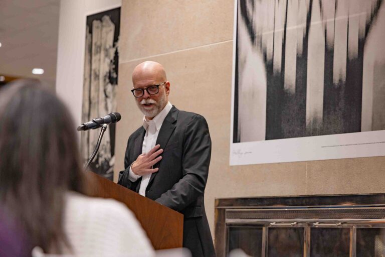 Bruce Strong, associate professor in Visual Communications at Newhouse and the Alexia Endowed Chair, speaks during the opening night of his Call to Me, Balkans photo exhibition in Panasci Lounge located on the third floor of Schine Student Center. The exhibition features photos, all of which were made on his iPhone, from his 2023 sabbatical and two successive trips to Bosnia. Claudia Strong, an adjunct in Visual Communications at Newhouse and also Bruce’s wife, curated and designed the exhibition.