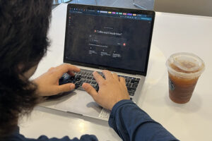 Man typing on computer with coffee