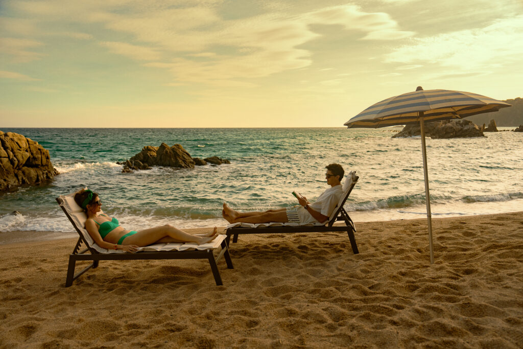 In People We Meet on Vacation two people lay on sun loungers on a beach.