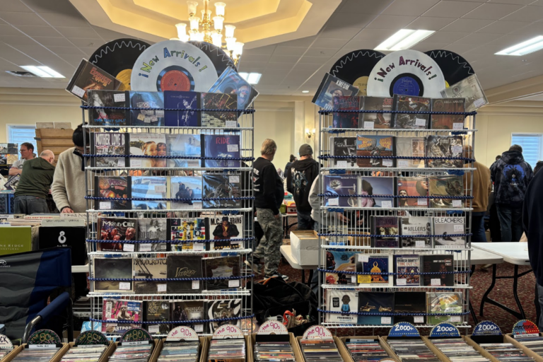 At the Syracuse Records and CD fair, two displays of "New Arrival" CDs sit on a table filled with CD cases.