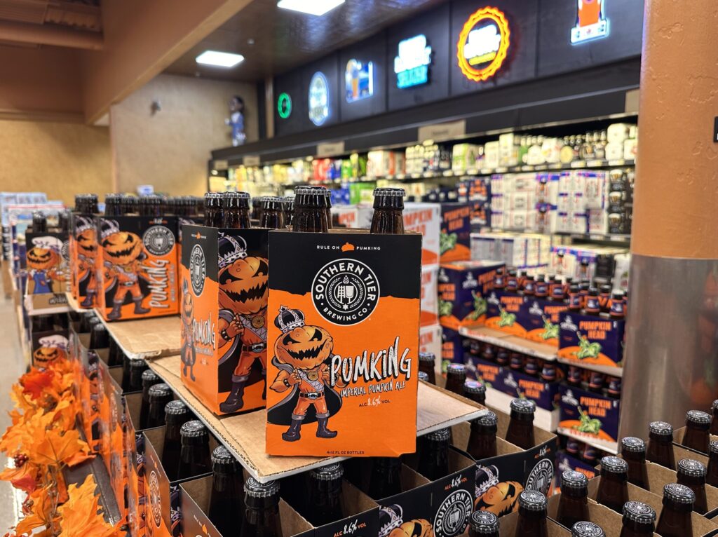 In a grocery store display a black and orange box features an image of a jack-o-lantern wearing a crown to promote Souther Tier Pumpking.