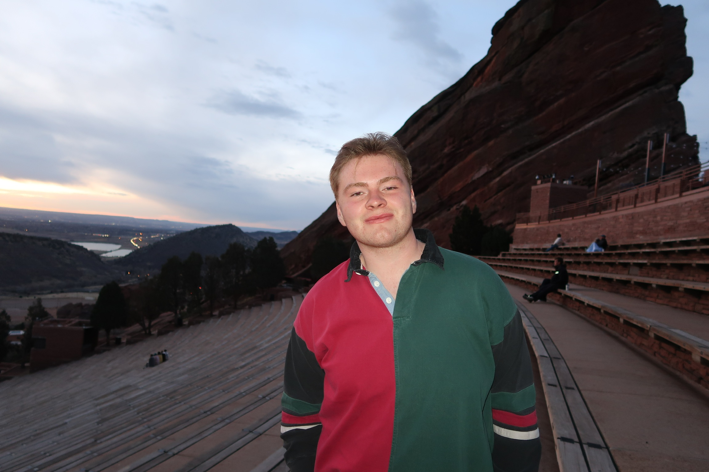 A photo of Syracuse University student and online college influencer, Spencer Howard standing in a green and red shirt by a cliffside.