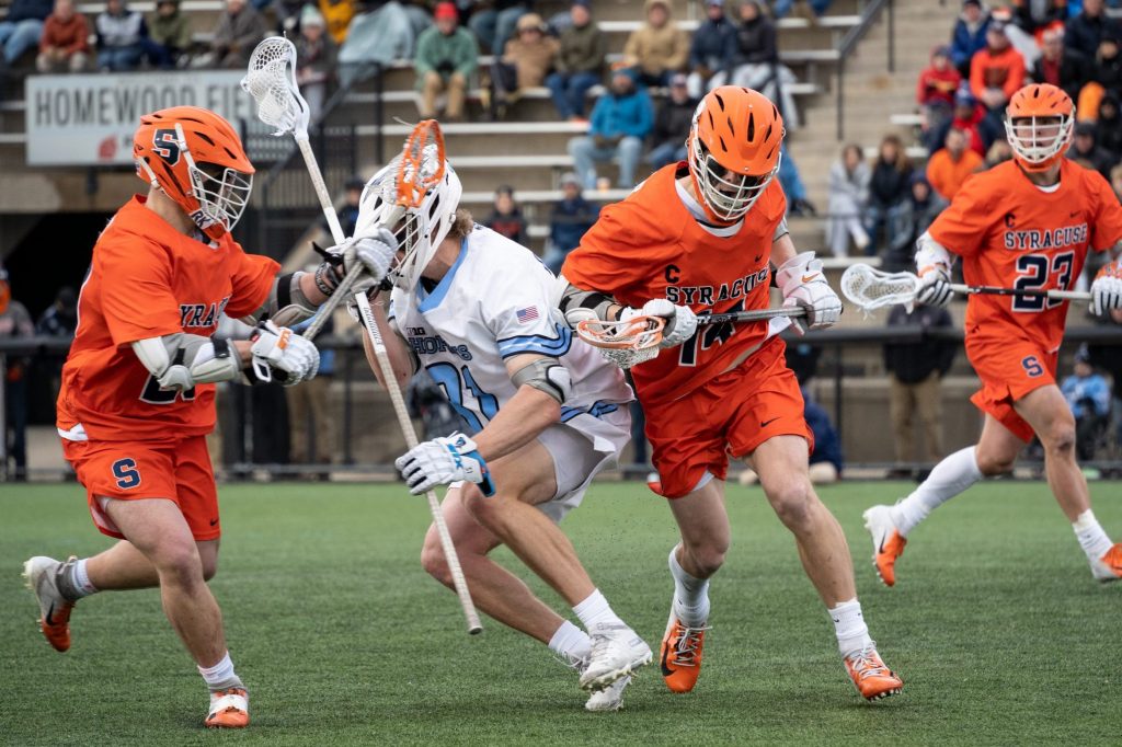 Freshman Tyler Cordes and Senior Captain Owen Seebold check a Johns Hopkins defender -- SU vs. Johns Hopkins - Lacrosse - March 13, 2022 - Baltimore, Maryland