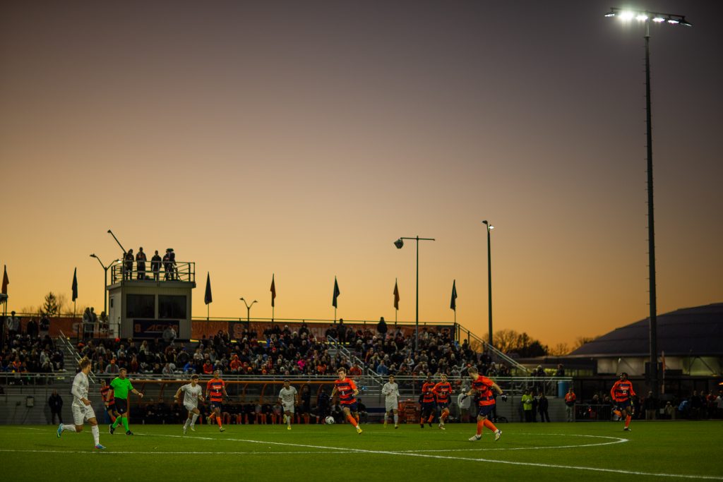 SYRACUSE, NY - NOVEMBER 9: The sun sets as Jeorgio Kocevski #8 of Syracuse Orange moves the ball against the Virginia Cavaliers during the ACC Semifinal at SU Soccer Stadium on November 9, 2022 in Syracuse, New York. (Photo by Isaiah Vazquez/The Newshouse)