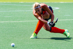 Field hockey player in orange shoots the ball